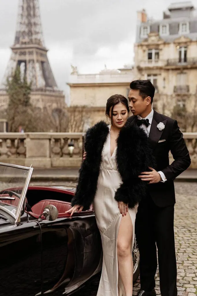 Bautpaar in Paris am Eiffelturm. Der Bräutigam mit roter Nelke als Boutonniere und Smoking (black tie).